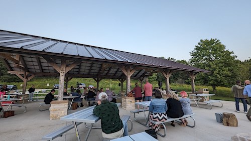 The park pavilion at Indian Lake County Park with County Board Supervisors seated at picnic tables